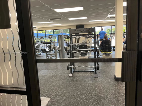 A gym area with exercise equipment and people working out.