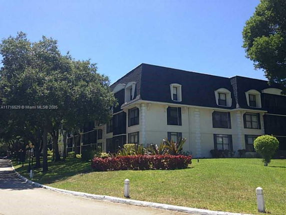 Front view of a multi-story residential building with black mansard roof and white walls.