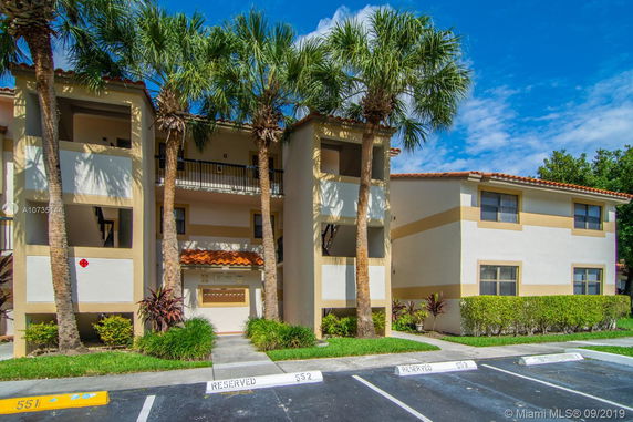 Front view of a multi-story apartment building with balconies and a tiled roof.