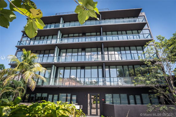 Front view of a multi-story building with large glass windows and balconies.