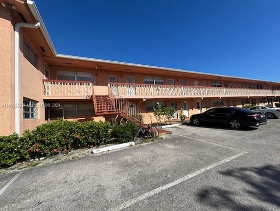 Front view of a two-story apartment building with exterior staircase and parking area.
