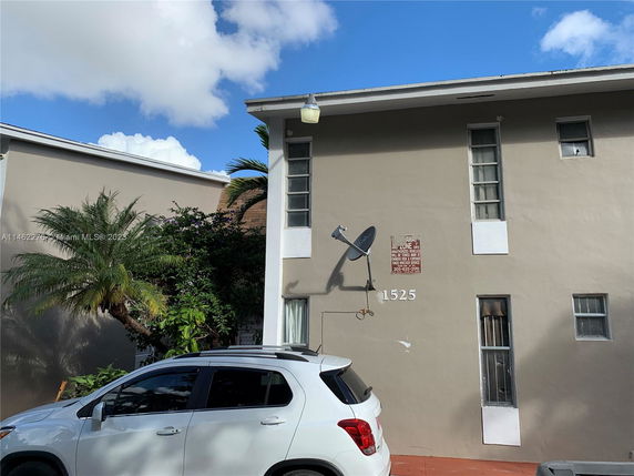 Front view of a two-story building with satellite dish and parking area.