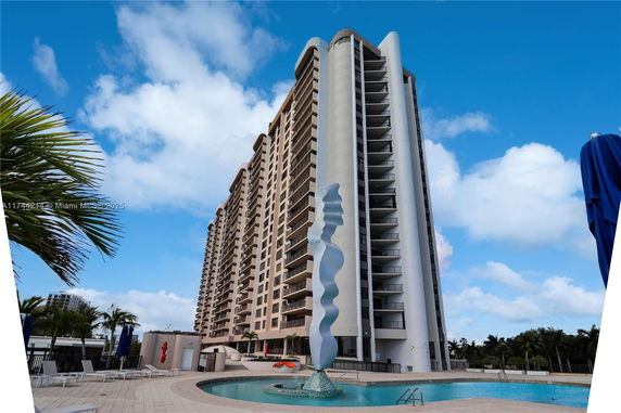 High-rise building next to a swimming pool with a sculpture feature.