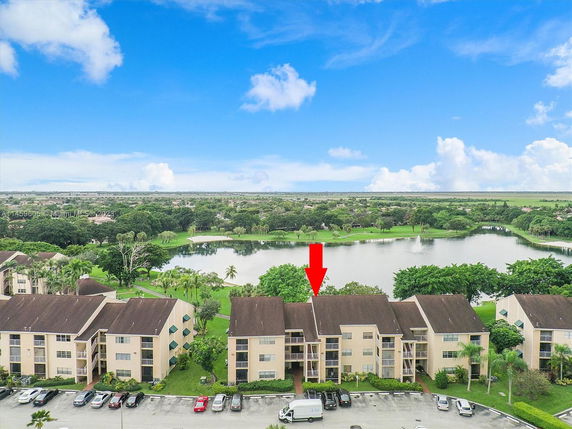 Aerial view of apartment buildings near a lake with parking area.