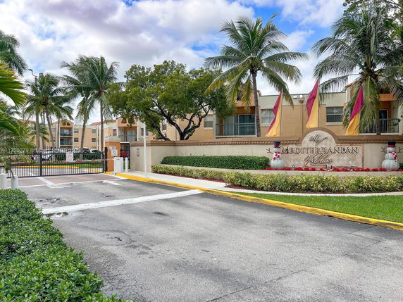 Front view of a residential building complex with gated entry and palm trees.