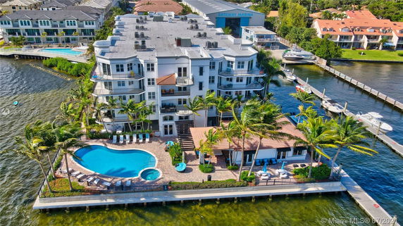 Aerial view of a multi-story waterfront building with a swimming pool and dock area.