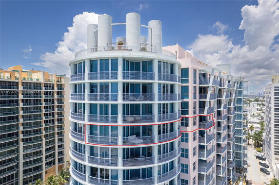 Front view of a modern multi-story building with curved balconies and large glass windows.