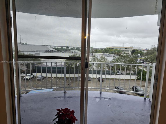 View from a balcony showing surrounding buildings and parked cars.