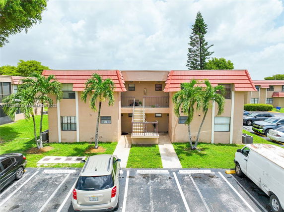 Front view of a two-story residential building with central staircase and parking area.