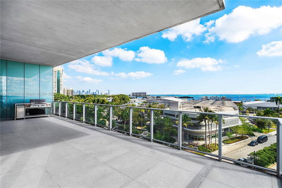 Panoramic view from a building's balcony overlooking a cityscape and coastline.