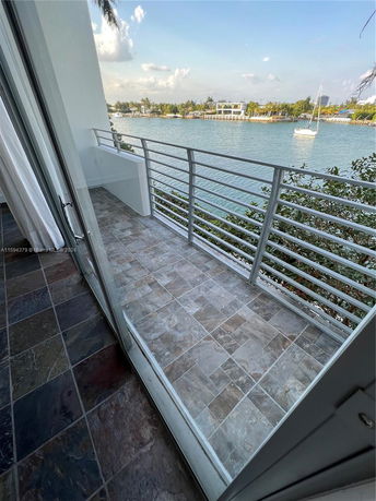 View from a balcony overlooking a body of water with boats and distant buildings.