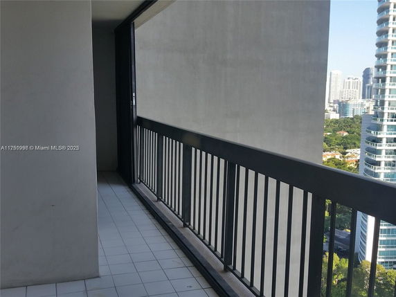 Balcony view with cityscape, featuring tall buildings and greenery.
