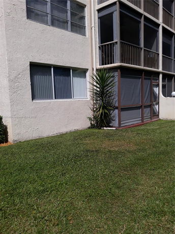 Exterior side view of a building with multiple windows and screened balconies.