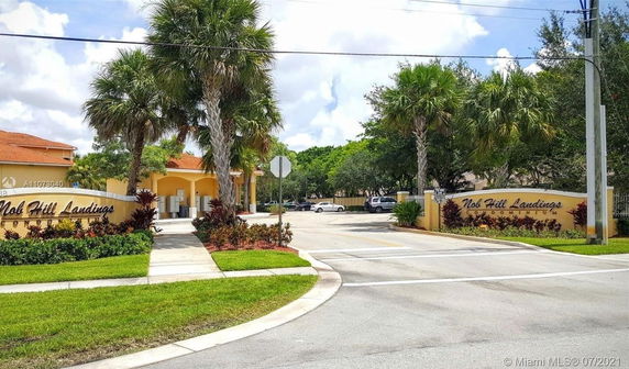 Entrance view of a condominium complex with palm trees and a sign.