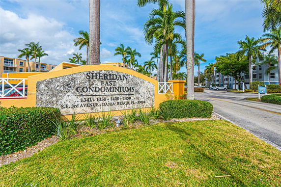 Front view of condominium entrance with signage and palm trees.