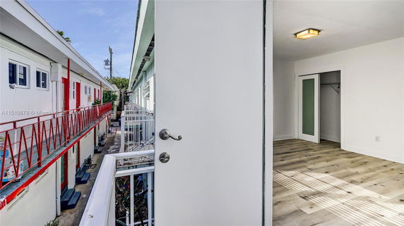 Exterior view showing the corridor and doorways of an apartment building with a view of an adjacent structure.