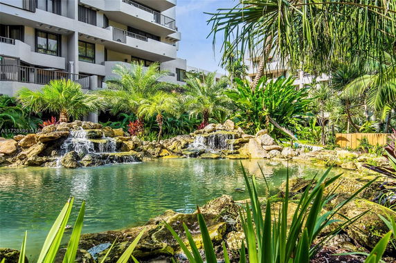 View of a building with lush greenery and a small waterfall pond in the foreground.