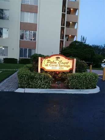 Front view of a multi-story apartment building with a sign reading 'Palm Court at Coral Springs 3101 - 3269' in front.