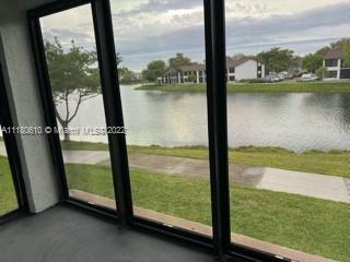View from inside a building looking out towards a lake and other buildings in the distance.