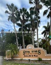 Entrance sign of Shoma Homes with palm trees in the background.