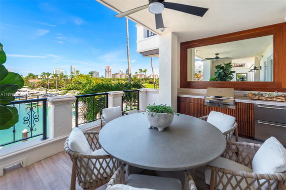 Balcony with a round table and chairs overlooking a lush landscape and high-rise buildings in the distance.