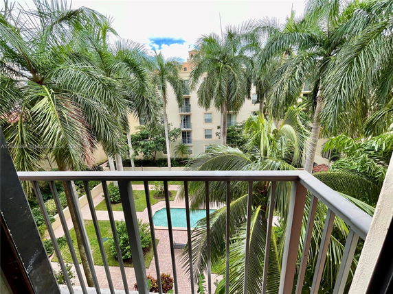 View from a balcony with palm trees and a building in the background.