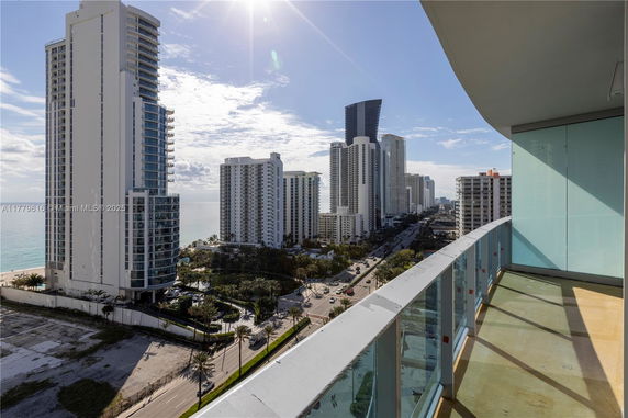 Panoramic view of high-rise buildings and coastline from a balcony.