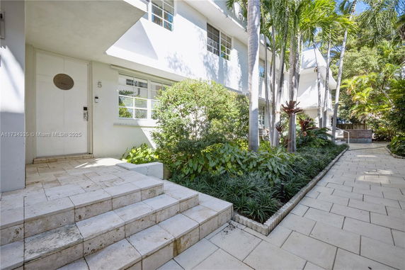 Front view of a building entrance with steps and surrounding greenery.