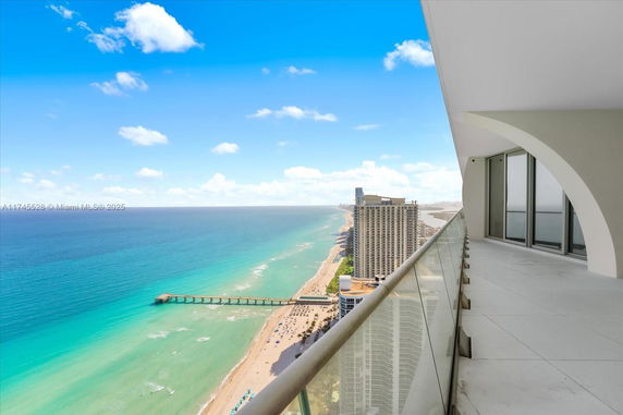 Panoramic view of a beach and ocean from a high-rise building balcony.