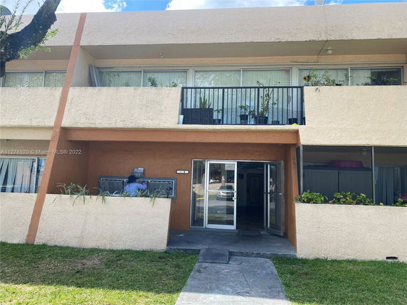 Front view of a two-story building with balconies and glass entrance doors.