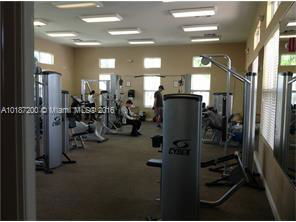 Indoor gym area with exercise equipment and people working out.
