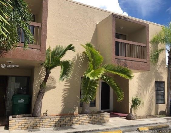 Front view of a two-story building with balconies and palm trees.