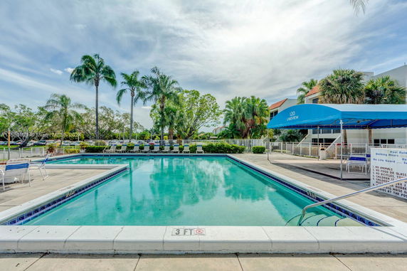 Outdoor swimming pool with surrounding deck chairs and a canopy area.