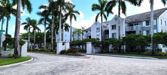 Front view of a multi-story residential building with balconies and landscaped entrance.