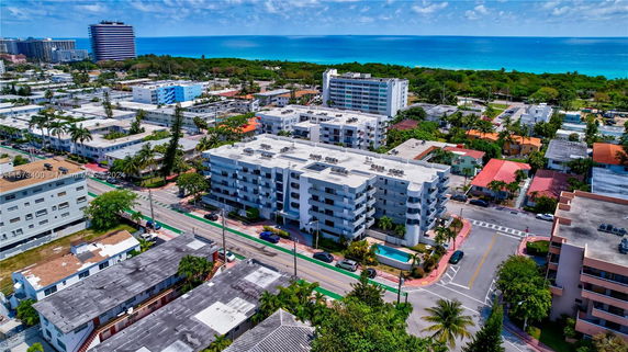 Aerial view of a coastal urban neighborhood with mid-rise residential buildings and the ocean in the background.