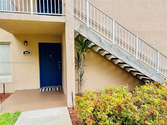 Exterior view of a building entrance with a blue door and adjacent staircase.