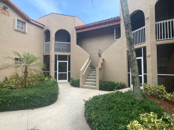 Front view of a two-story building with an external staircase and multiple entrances.