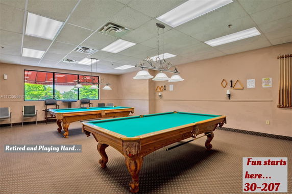 Room with billiard tables and seating area.