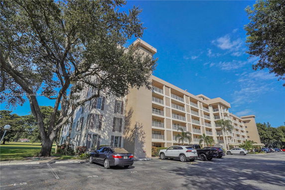 Front view of a multi-story residential building with a parking area in front.