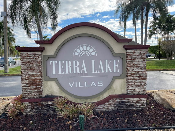 Signage for Terra Lake Villas at a landscaped area with palm trees.