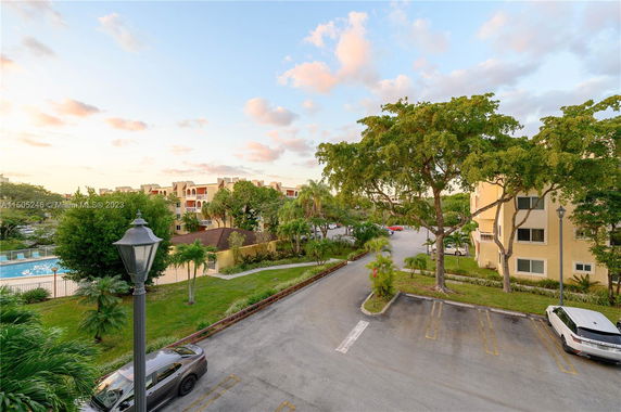 View of apartment buildings surrounded by trees and parking lot.