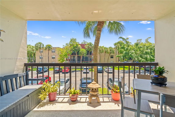 View from a balcony overlooking a parking area and residential buildings.