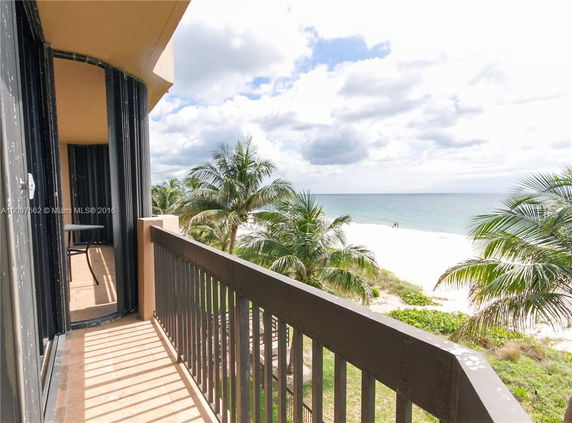 View from a balcony overlooking a sandy beach and ocean.