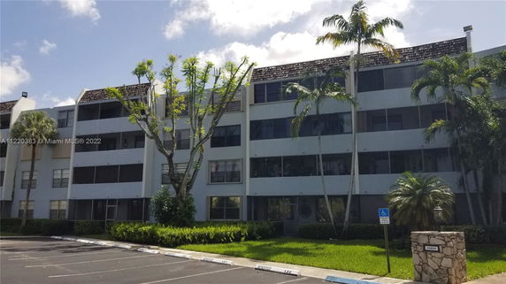 Front view of a multi-story residential building with a parking area.