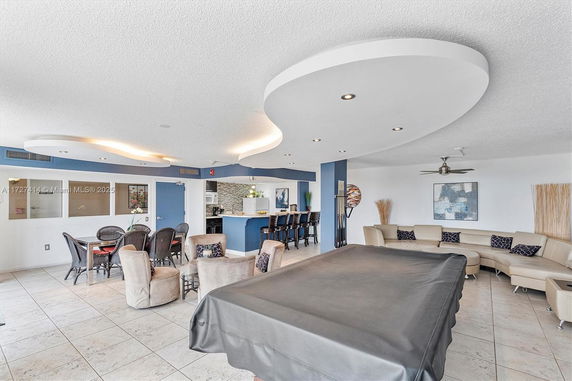 Interior view of a recreational room with seating, a pool table, and a bar area.