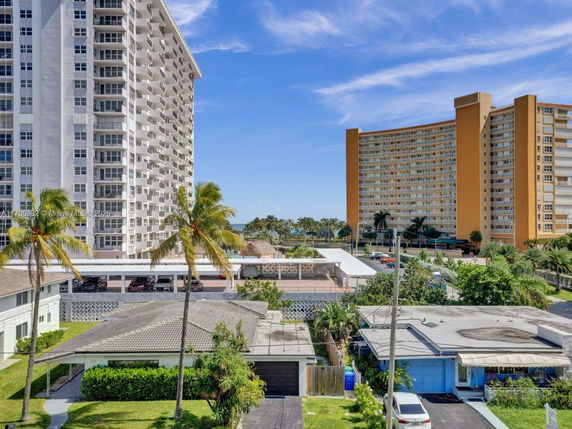 View of a multi-story building and surrounding residential area with palm trees.
