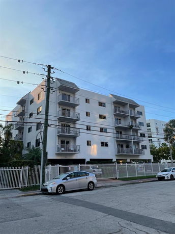 Front view of a multi-story apartment building with balconies and a gated entrance.