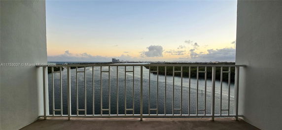 Panoramic view from a balcony overlooking a body of water and distant cityscape.