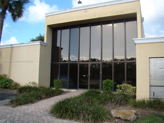 Front view of a building with large glass windows and beige walls.