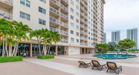 Outdoor view of a multi-story apartment building with a swimming pool in the foreground.